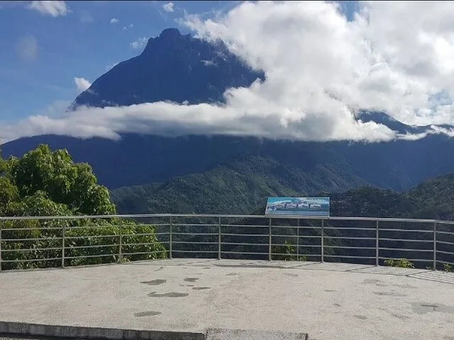 Plateforme d'observation avec garde-corps métalliques surplombant le mont Kinabalu partiellement couvert de nuages