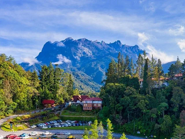 Vista amplia de los edificios y el estacionamiento del Parque Kinabalu con el monte Kinabalu al fondo