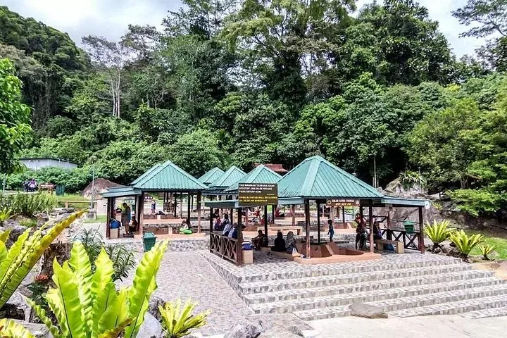Menschen entspannen in Open-Air-Thermalbecken mit grünen Dächern in Poring Hot Springs