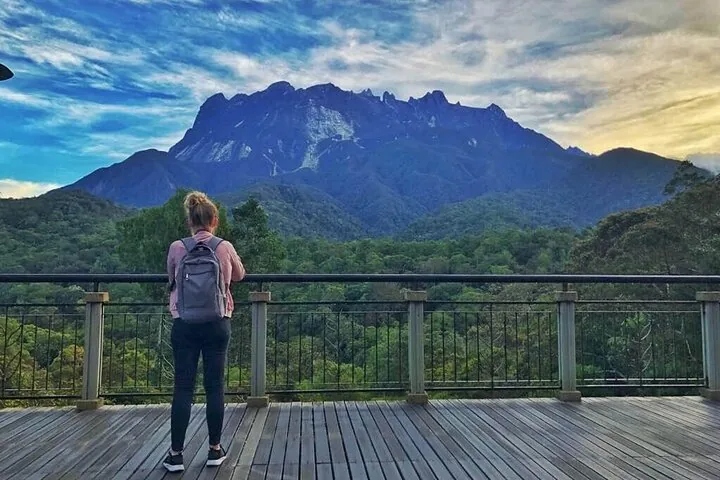 Mujer de pie en una plataforma de madera contemplando el majestuoso Monte Kinabalu