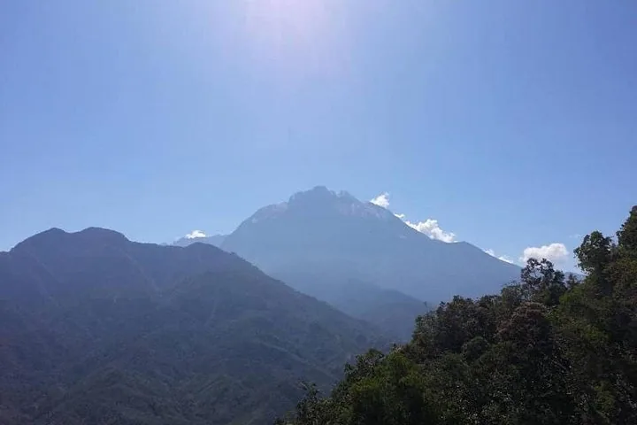 Distant view of Mount Kinabalu with a clear blue sky and sun glare